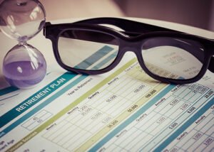 Digital marketing strategy plan with eyeglasses and an hourglass on a desk.